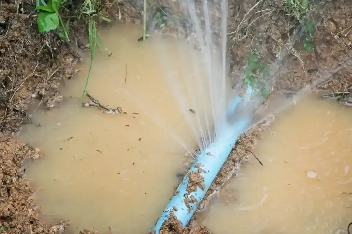 Main water line leak detection: A broken pipe spewing water into a muddy trench.