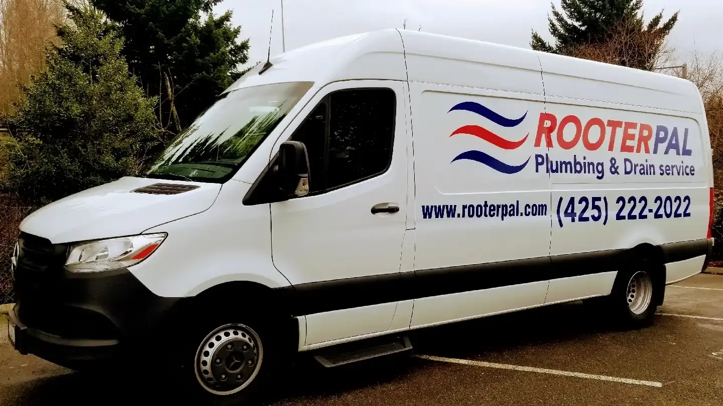 A white Rooter-PAL Plumbing & Drain Service van, with the company logo, website, and phone number, parked outdoors.