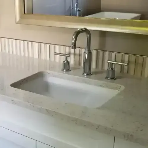 A stylish bathroom vanity with a white undermount sink, a polished chrome faucet with two separate handles, and a light-colored speckled countertop.