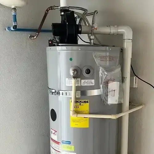 A newly installed grey residential water heater with an "EnergyGuide" label, connected to white PVC and copper pipes, and a recirculation pump at the top.